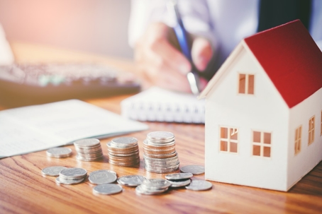 coins on desk with white house and red roof
