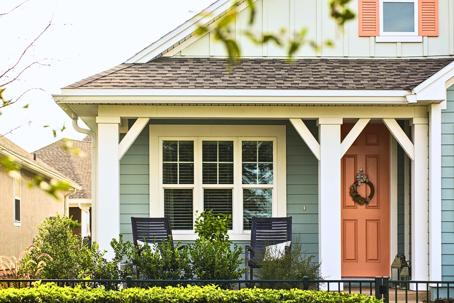 A home exterior with light blue siding, complemented by a peach-colored door and matching window accent.