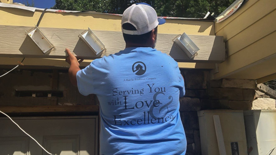 A construction worker installs siding on a house.