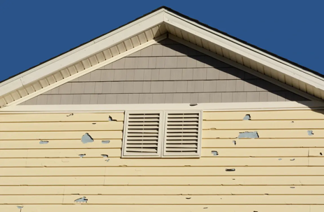Hail damage to vinyl siding is visible in this close up of a home's exterior.