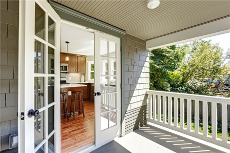 A photograph of an open French door leading from a balcony into a kitchen.