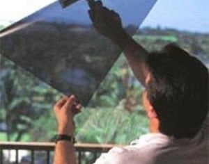A man is applying window film to a glass pane