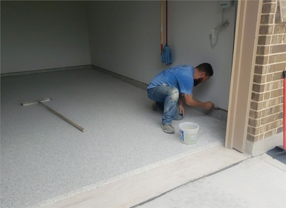 A man applies epoxy coating to a garage floor.
