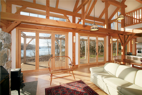 A large room with light wood framing features floor-to-ceiling glass doors opening to the outside.