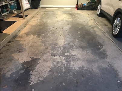 A garage floor shows signs of wear with peeling and discoloration; the need for epoxy coating is apparent.