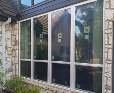 A set of four large windows are installed in a stone wall.