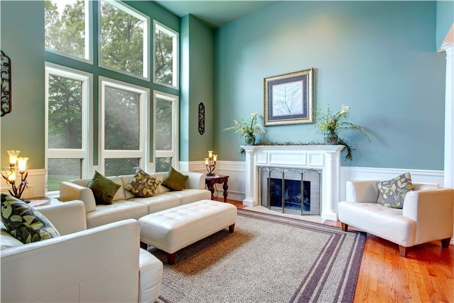 A bright, open living space with large windows, featuring light-colored furniture and a fireplace.