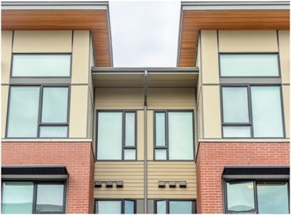 A multi-unit building featuring brick and siding with many windows.