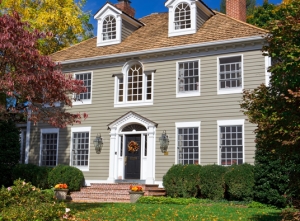 An exterior of a two-story home with a gray siding and a black door.