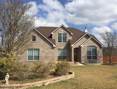 a photo of a single-story brick home with a dark shingle roof and many windows.