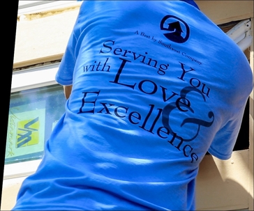 A construction worker wearing a blue t-shirt is seen installing a window.