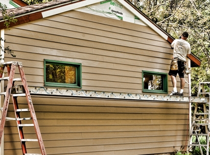 A man installs siding on a house.