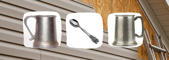 Two pewter mugs flank a silver spoon on a textured surface.