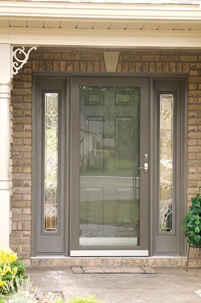 A brown front door with decorative glass sidelights and a small welcome mat.