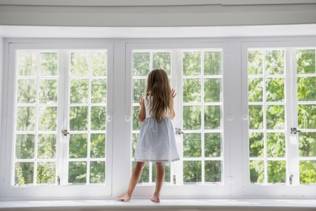 A young girl faces a bright window