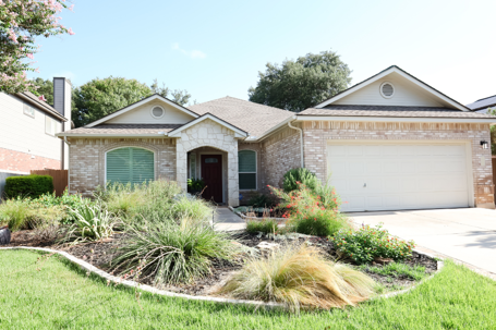 Single-story brick house with native landscaping and a lawn