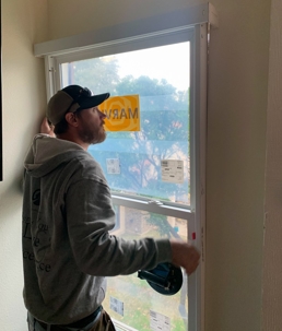 A window installer is seen putting in a new window pane.