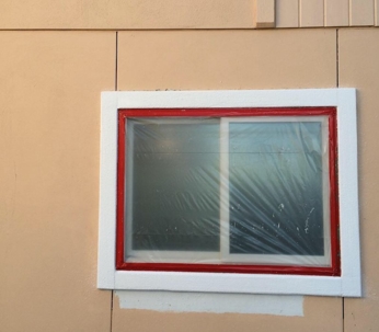 An image of a window during painting prep, covered with plastic.