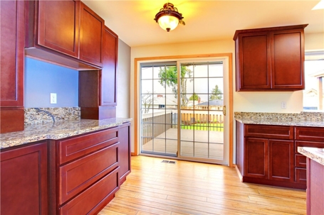 A kitchen area with wooden cabinets and granite countertops leads out to a deck through a sliding glass door.