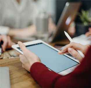A close-up shows hands using a tablet and stylus, likely during a meeting.