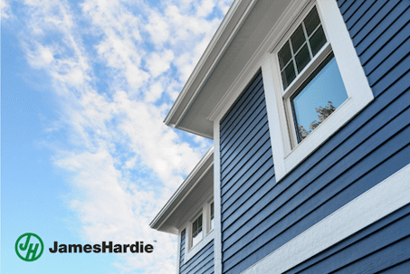 This photo shows a house with windows and blue sidings