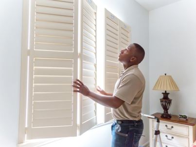a man fixing a window shutters