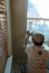 A person is caulking a window with a caulking gun