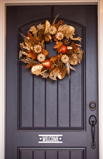 A front door with a fall wreath and welcome sign.