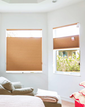 Light brown top down bottom up window shades with the top drawn down to expose some sunlight in a living room space.