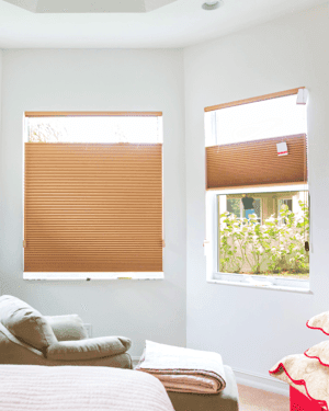 Light brown top down bottom up window shades with the top drawn down to expose some sunlight in a li…