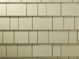 A close up of straight-edge beige shingle siding where the siding is made up of rectangles of varying widths laid on the same horizontal line.