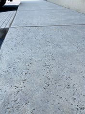 A close up of a sidewalk with a rock salt concrete finish where there are small holes intentionally in the concrete.