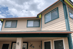 A home with light tan horizontal siding and green soffit and fascia. The soffit and fascia are highlighted yellow and red to show soffit and fascia on a home. 