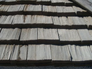 A close up of split shake siding where the siding is made up of small wooden shingles that have uneven edges and texture.