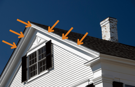 A white home with a black roof and orange arrows pointing to the fascia boards on the home. 