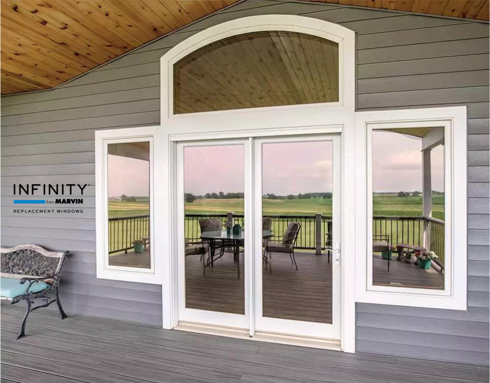 White picture and round top windows from Infinity from Marvin surrounding a white patio door against gray lap siding with the Infinity from Marvin logo to the left of the image. 