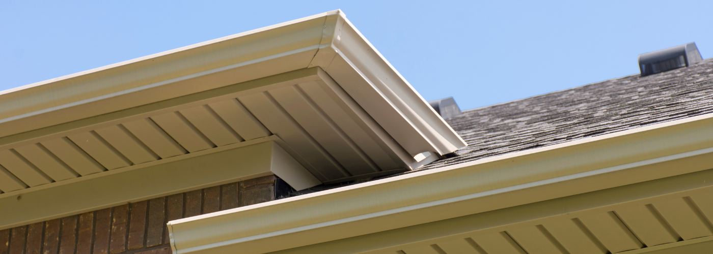 The top of a roofline on a brick home, showing the soffit and fascia of the home. 