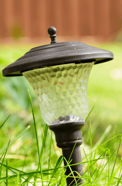 A small solar path light stuck in the grass.