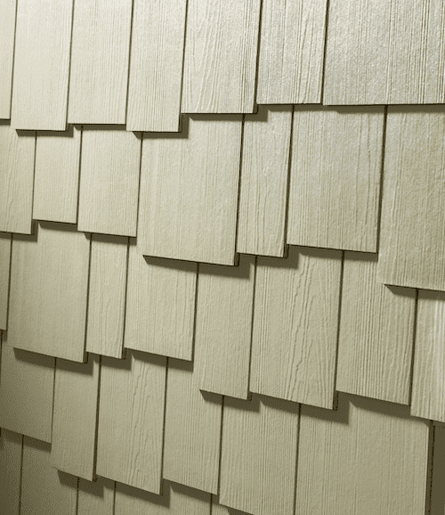 Close-up of staggered shingle siding in an off-white color with a cedar finish.