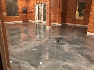 A room with wood walls with a grey epoxy coating that looks like marble.