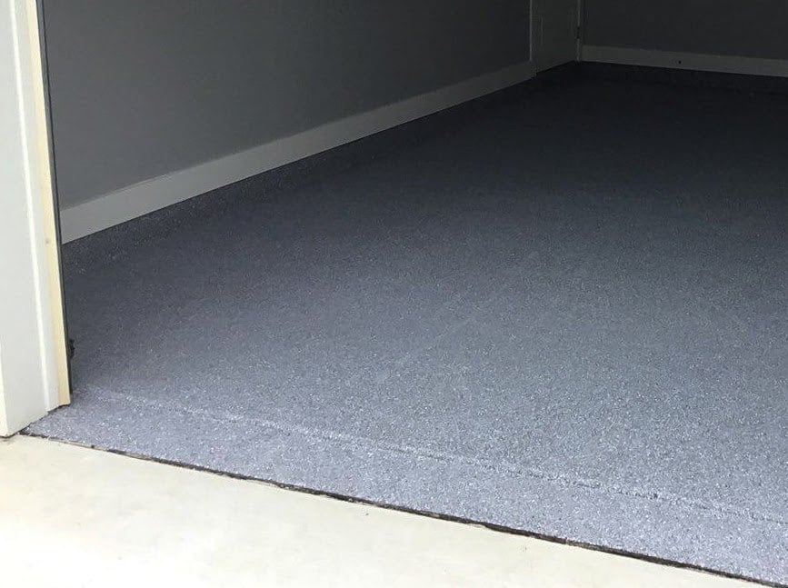A garage floor with a blue colored coating that goes right outside the garage door.
