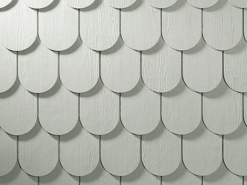 Close-up of scalloped shingle siding in white with a cedar finish.