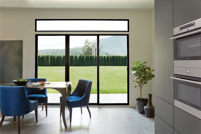 Marvin Warranty A kitchen/dining room area with blue velvet chairs at table in front of a large patio sliding door w…