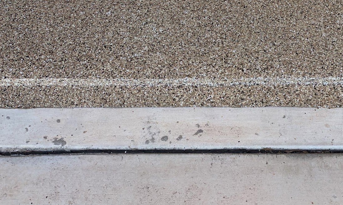 A close up of a garage floor coated a brown color halfway down a dip near the garage door.